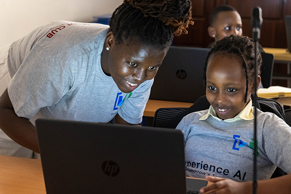 Young woman helps student by computer