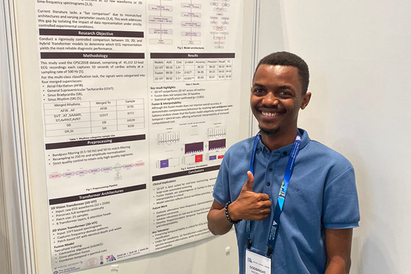 A student giving the thumbs up in front of his poster